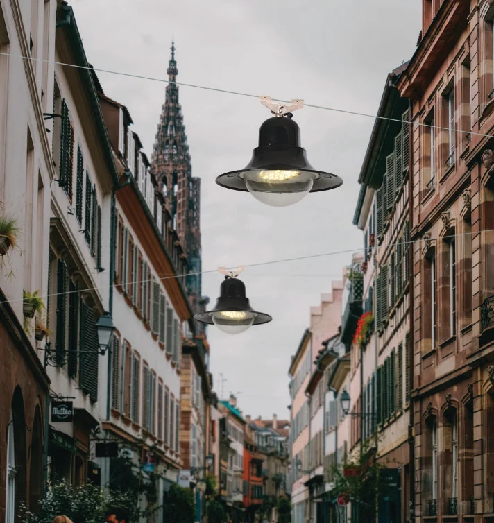 LUXIFIC catalogue application visual showing BELL decorative suspended luminaires along a pedestrian street