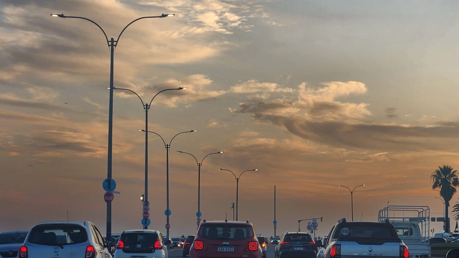 LED luminaires on double-arm poles above a busy roadway in South America at dusk